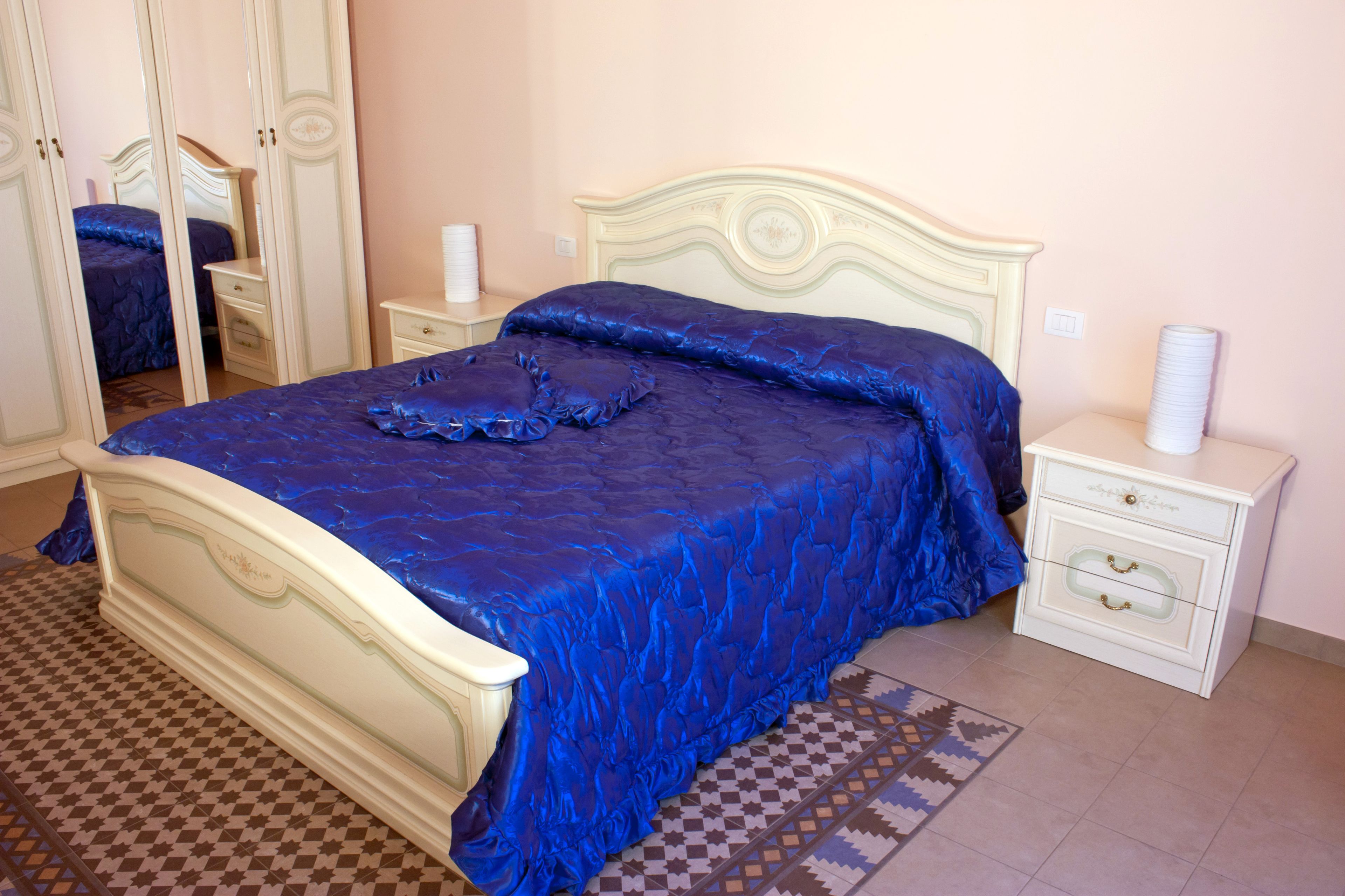 A bedroom with a bed, nightstands, a dresser, and a mirror.