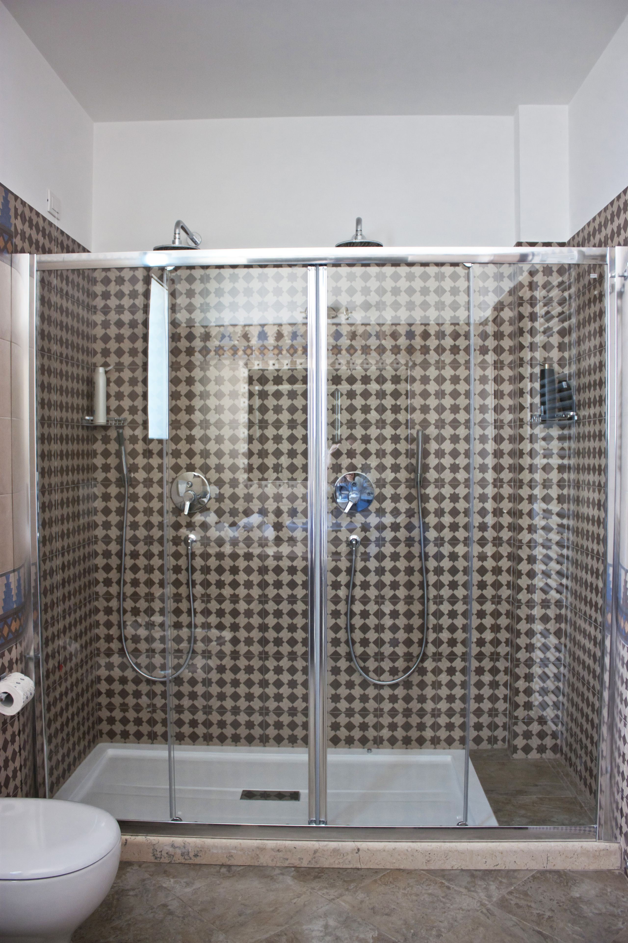 A walk-in shower with a glass door, tiled walls, and a toilet to the left.