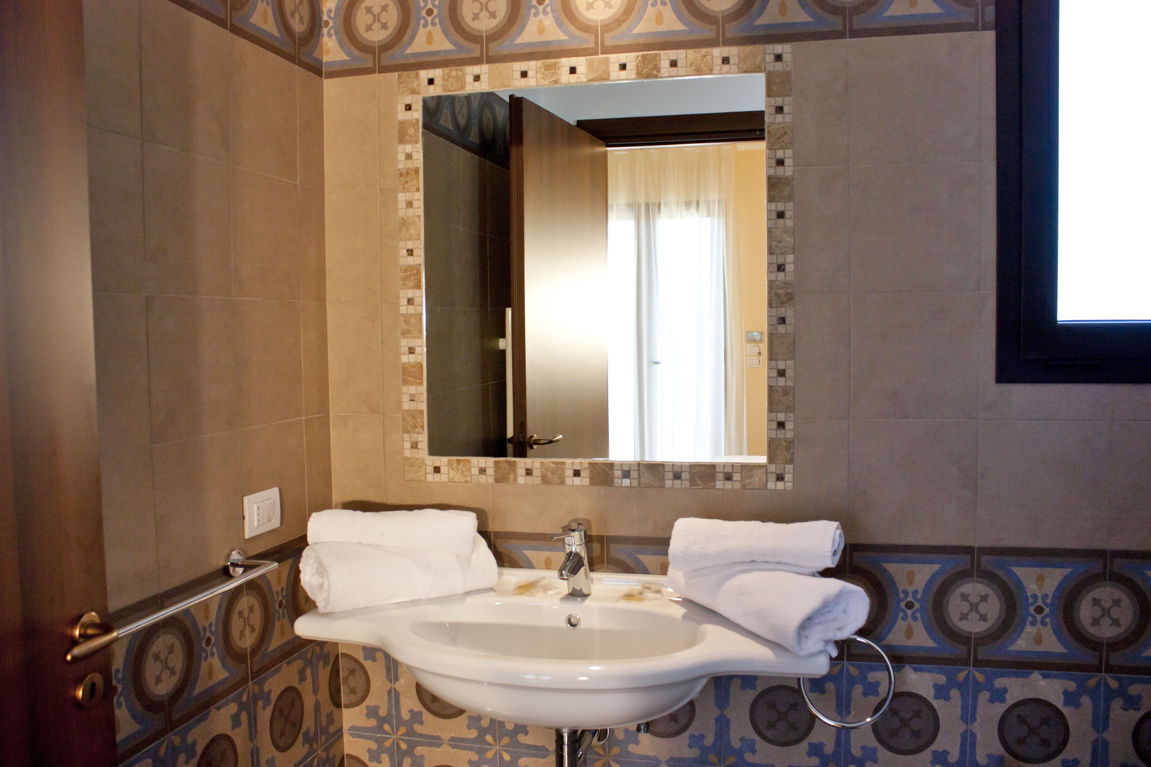 A bathroom with a sink, mirror, and patterned tiles.