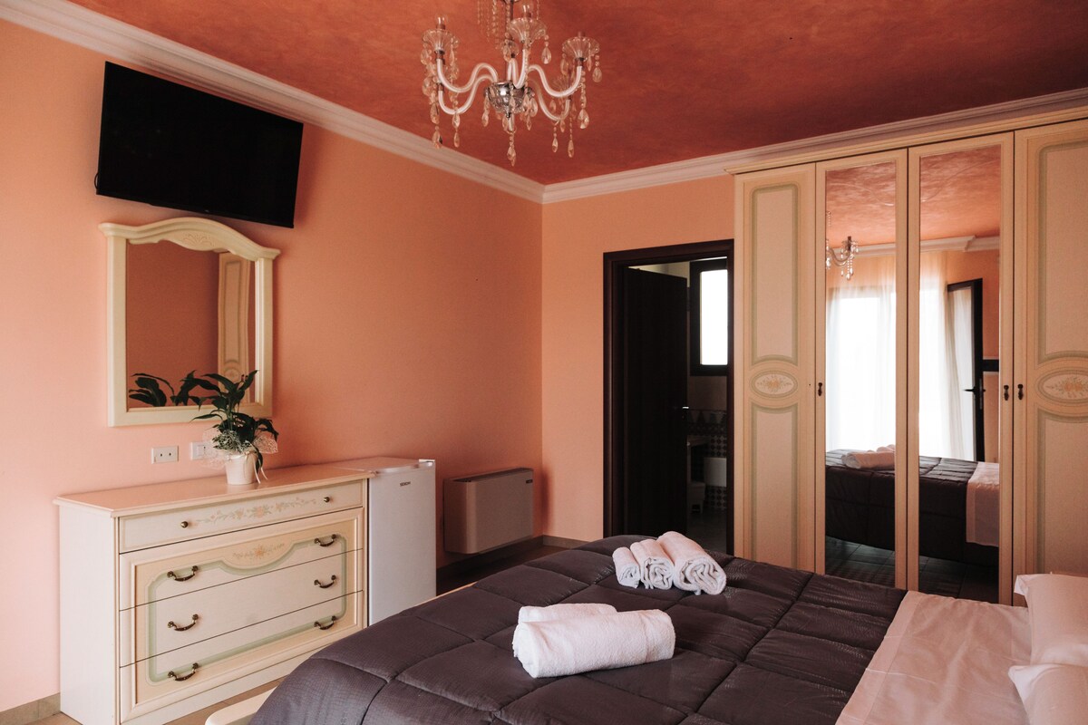 Un dormitorio con una cama grande, un aparador, un televisor y un espejo.