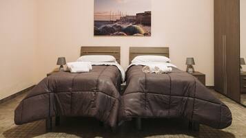 A double bed with a headboard, a bedside table with a lamp, and a painting of a coastal scene on the wall.