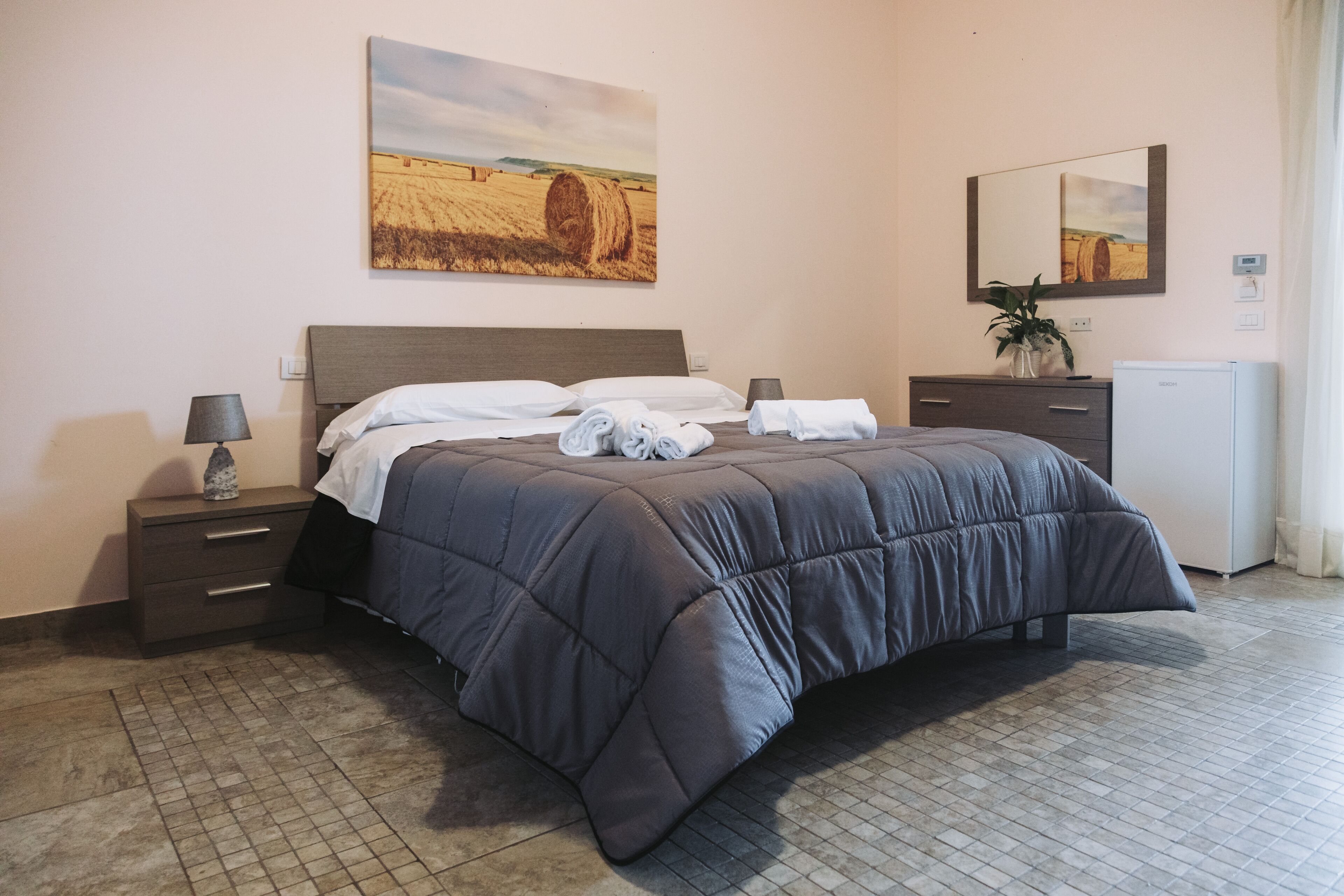Une chambre à coucher comprenant un lit, des tables de chevet, une commode, un miroir et un radiateur fixé au mur.