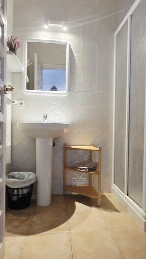 A bathroom with a sink, mirror, and a small shelf. - Apartamentos Turísticos Casin (Formentera)