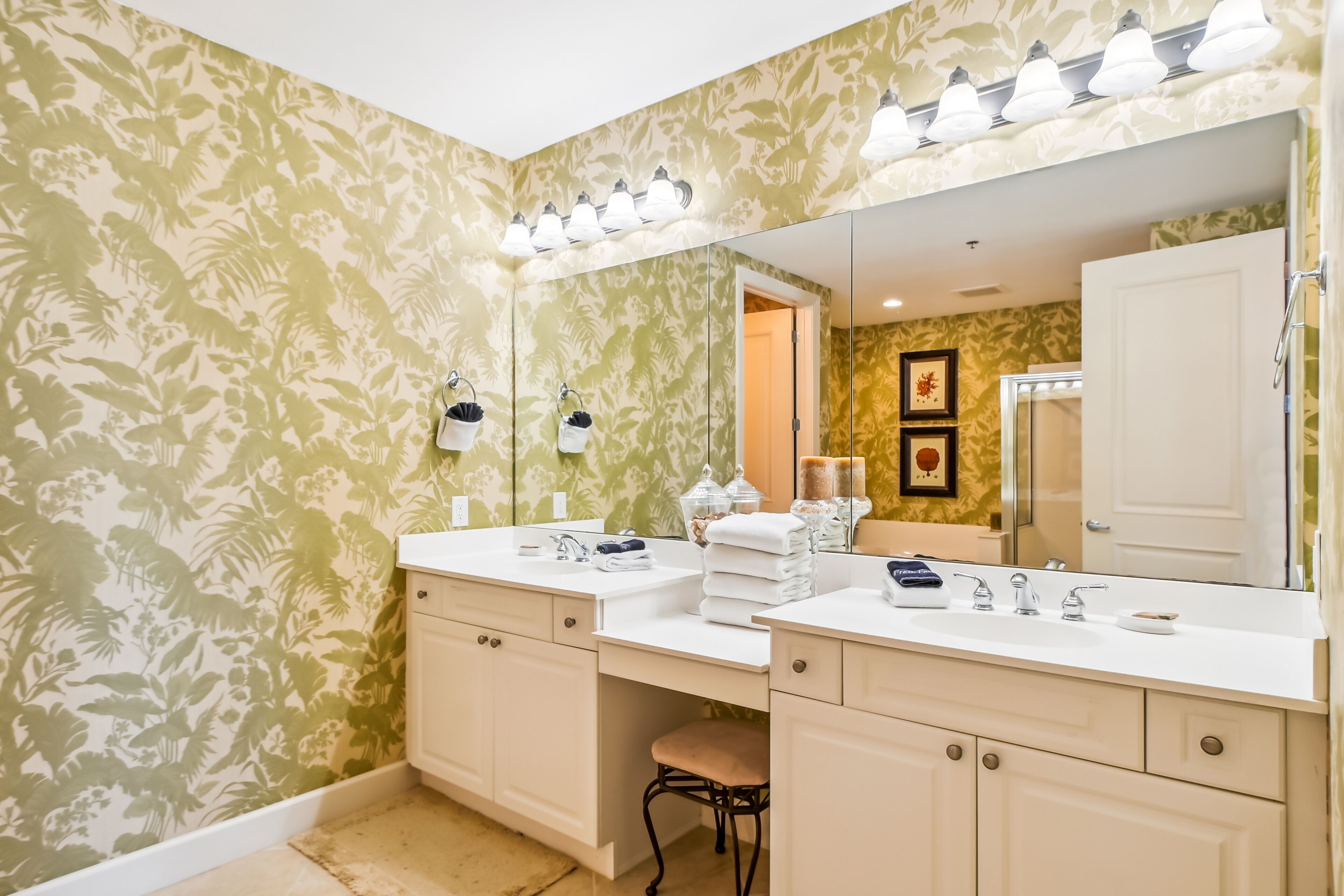 A bathroom with a large mirror, two sinks, and a vanity with drawers.