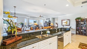 A spacious kitchen with a large island, white cabinetry, and a view to the living area.