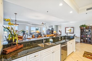 Kitchen features a large island with a sink and granite countertop, complemented by white cabinetry and a dining area with outdoor views.