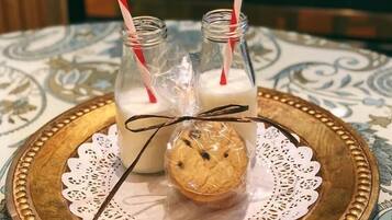 A tray with two milk bottles and a cookie on a tablecloth with a lace doily.