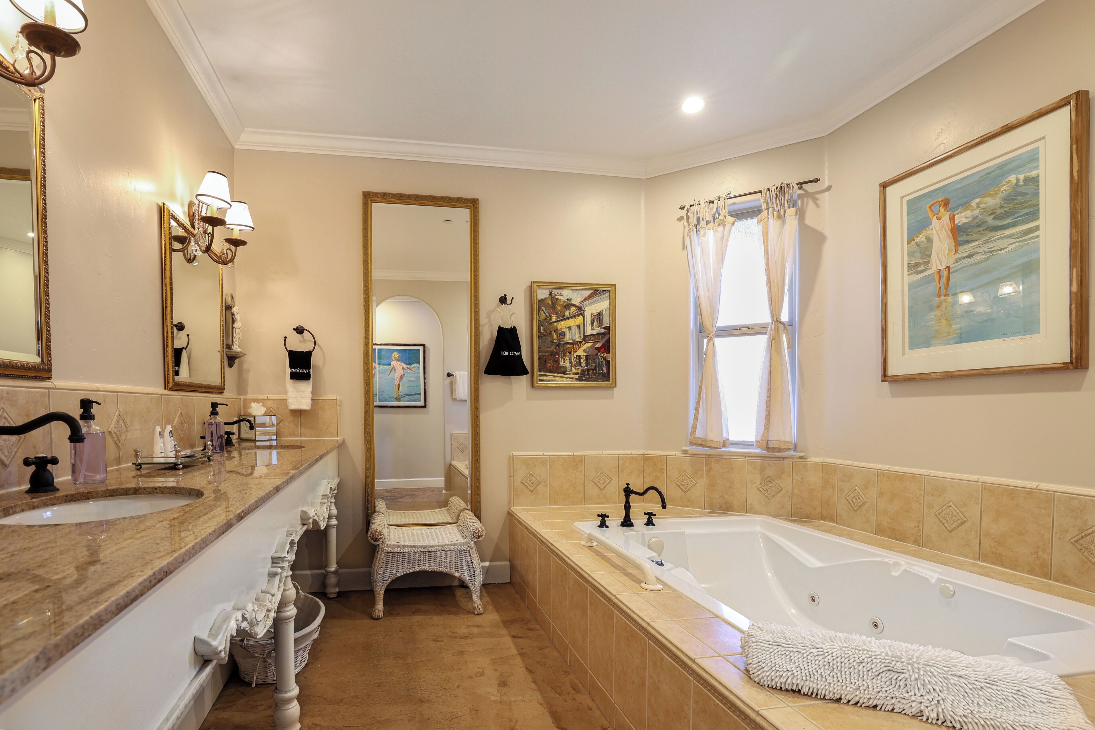 Un baño espacioso con una bañera grande, un lavabo doble y una silla de mimbre.