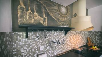 Uma cozinha com revestimento de azulejos na parede, luminária pendente e prateleira com utensílios de cozinha.