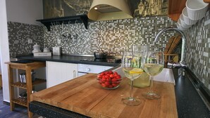 A kitchen with a wooden countertop, a bowl of cherries, and two glasses of white wine. - Lagom Apartments (Rakovica)