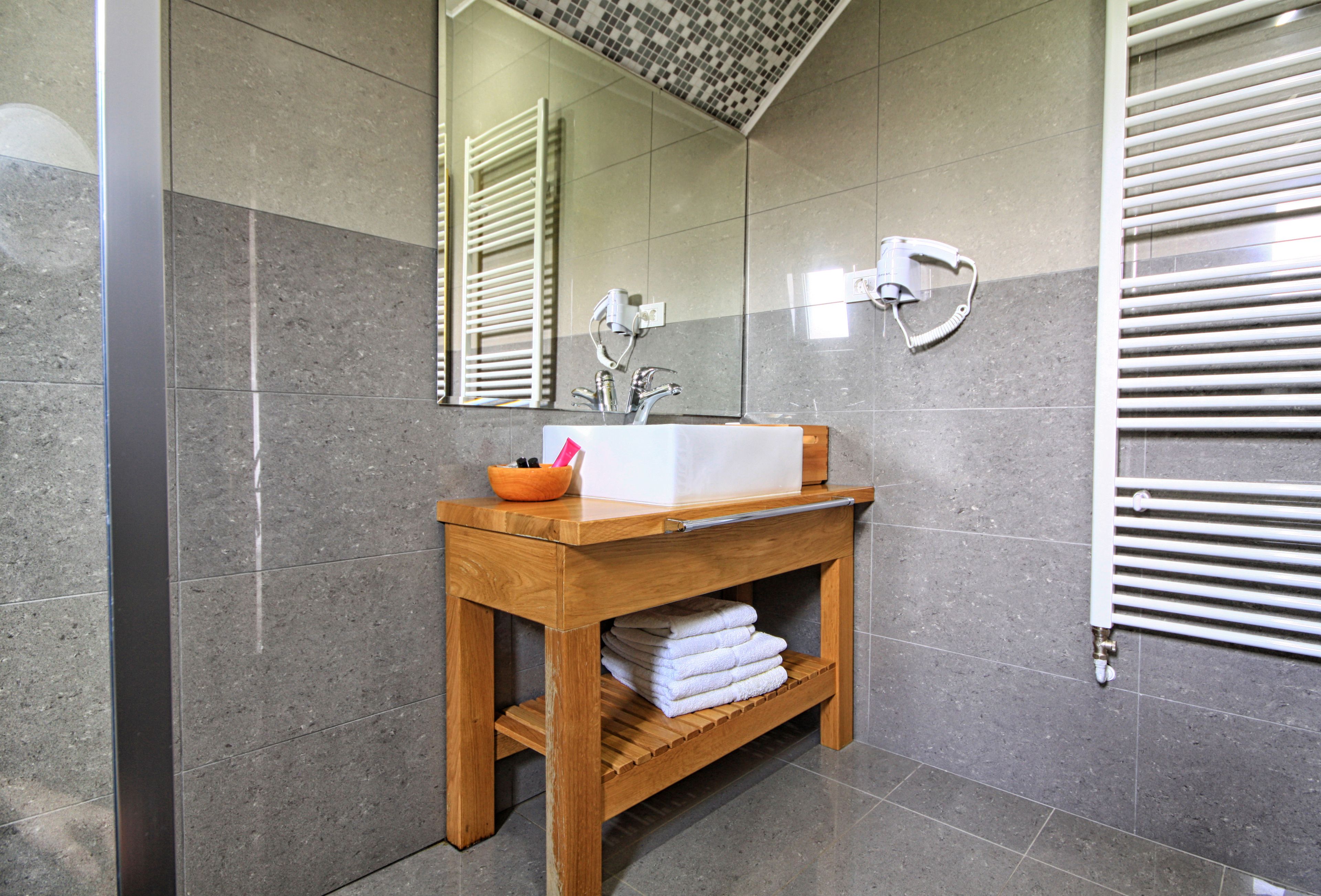 A bathroom with a wooden vanity, a sink, and a mirror.