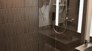 A modern bathroom with a glass shower enclosure, a built-in sink, and a towel rack.