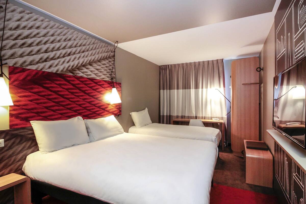 A hotel room with a large bed, two bedside tables, a desk, and a chair.