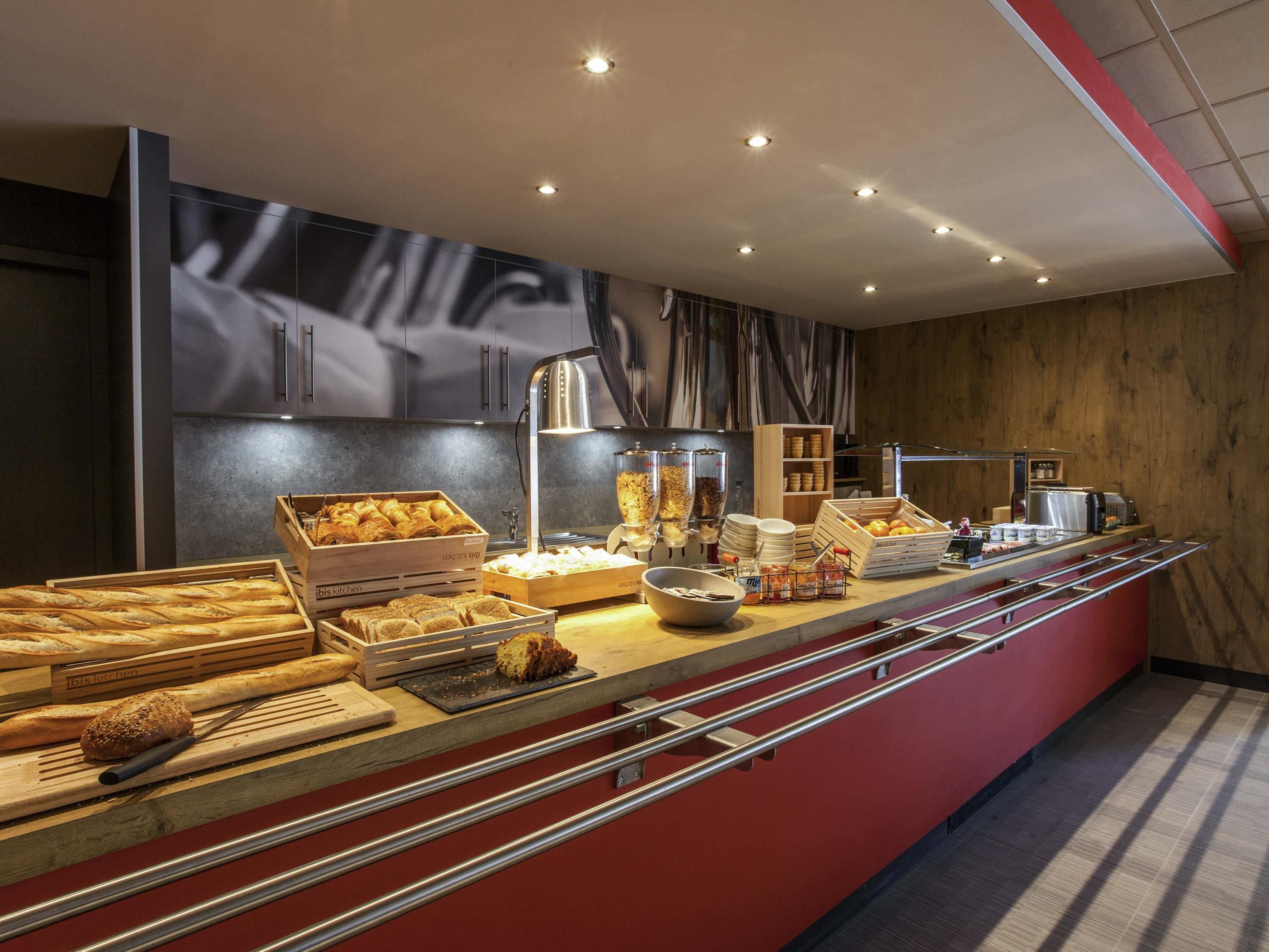 A breakfast buffet with various bread, pastries, and beverages.