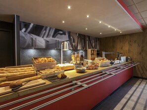 Un bufé de desayuno con panes, bollería y bebidas variadas.