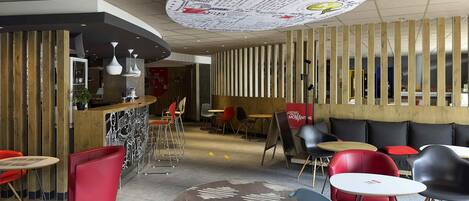 Ein modernes Interieur mit gewölbter Decke, Holzvertäfelung und einer Mischung aus roten und grauen Sitzmöbeln.