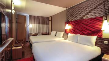 Ein Hotelzimmer mit zwei Betten, einem Fernseher, einem Schreibtisch und einem roten Teppich.