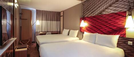 Habitación de hotel con dos camas, televisión, escritorio y alfombra roja.