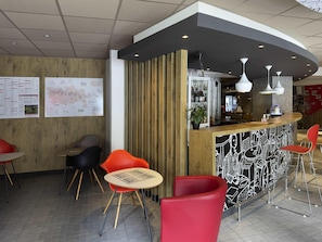 A modern bar area with a curved counter, red chairs, and a menu board on the wall. - ibis Cahors (Cahors)