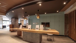 A reception desk with a wooden counter and a stone base, flanked by two pendant lights. - ibis Cahors (Cahors)