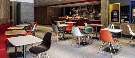 A modern restaurant with a mix of seating options including tables and booths, a visible kitchen area, and a bar.