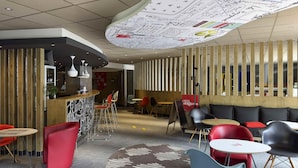 A modern interior with a curved ceiling, wooden paneling, and a mix of red and grey seating. - ibis Cahors (Cahors)