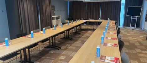 A conference room with a long table, chairs, and water bottles.