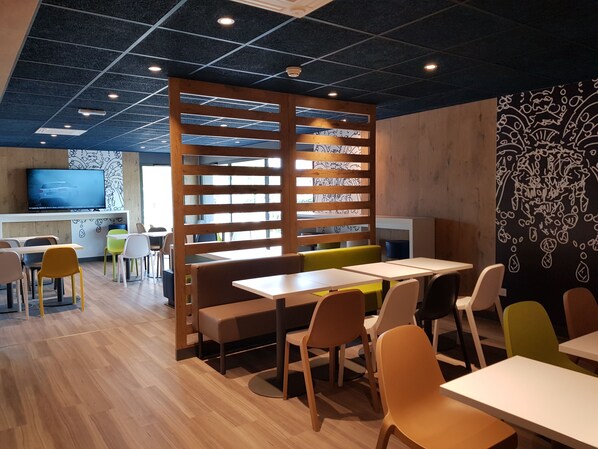 Un comedor moderno con separadores de madera, mesas y sillas.