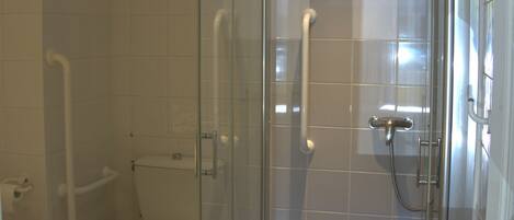 A modern bathroom with a glass-enclosed shower, a toilet, and a bidet.