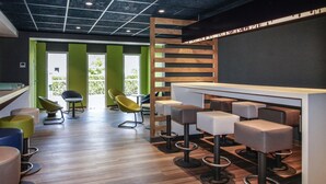 A modern bar area with stools, a counter, and a view of greenery outside. - ibis budget Cahors (Cahors)