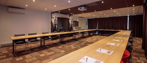 A conference room with a long table, chairs, and a projector.