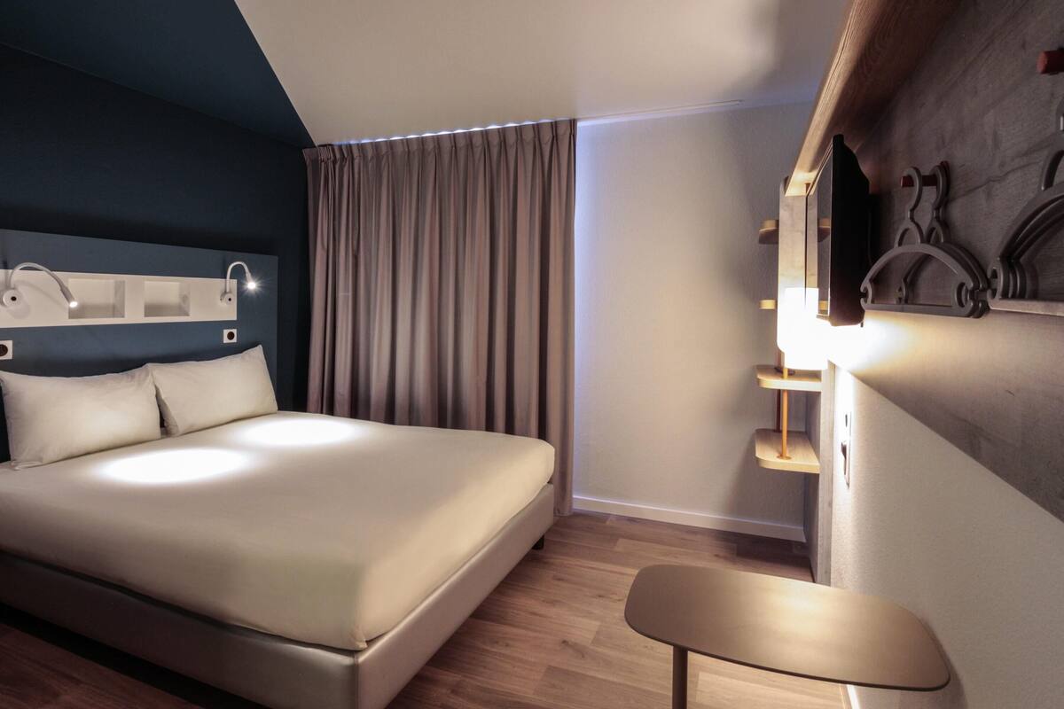 Ein modernes Hotelzimmer mit einem großen Bett, einem Schreibtisch und einem Spiegel.