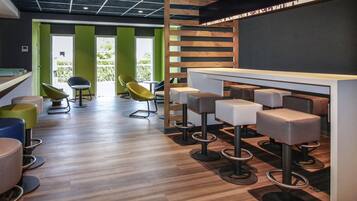 Uma área de bar moderna com banquetas, balcão e vista para o verde lá fora.
