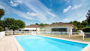 A rectangular swimming pool with a white fence, surrounded by a paved patio. - ibis budget Cahors (Cahors)