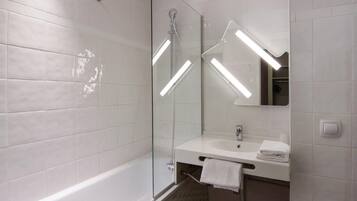 Une salle de bain moderne avec une douche à parois de verre, un lavabo blanc et un miroir.
