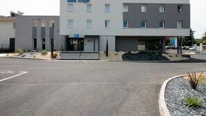 A modern building with a sign reading "Ibis Budget". It features a flat roof, multiple windows, and a small entrance with steps. - ibis budget Cahors (Cahors)