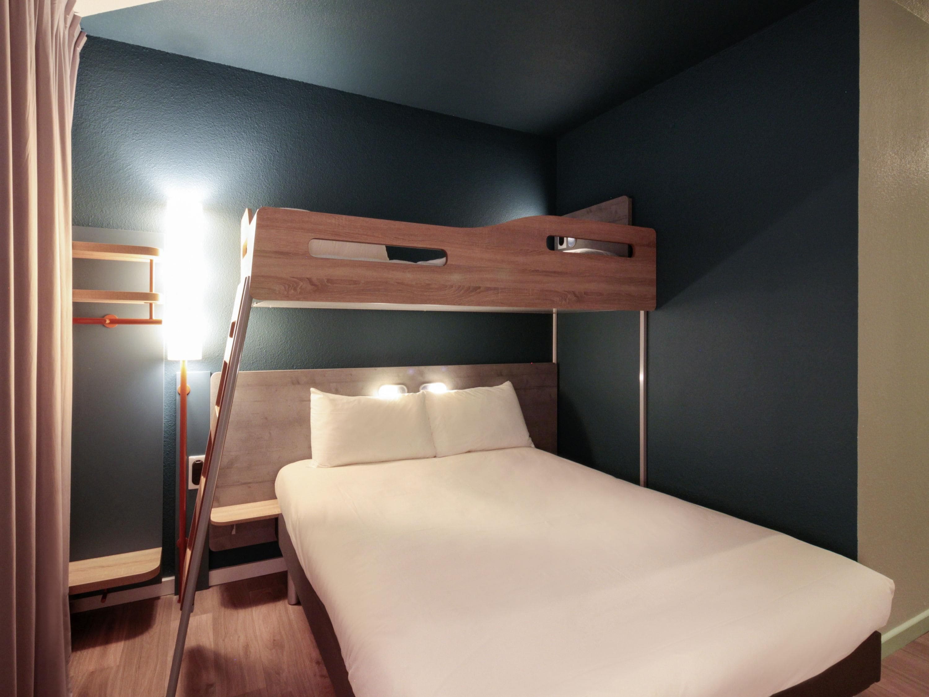 A bunk bed with a wooden headboard, a bedside table, and a lamp.