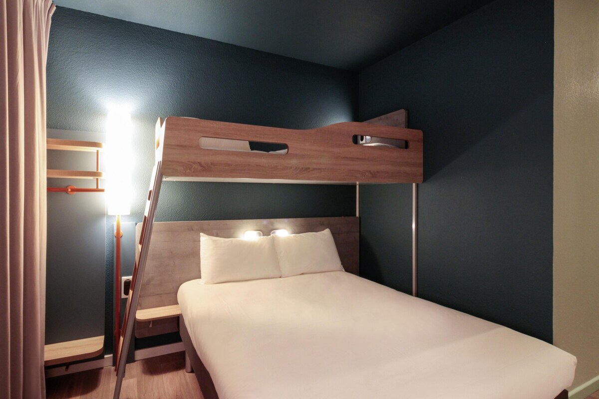 A bunk bed with a wooden headboard, a bedside table, and a lamp.
