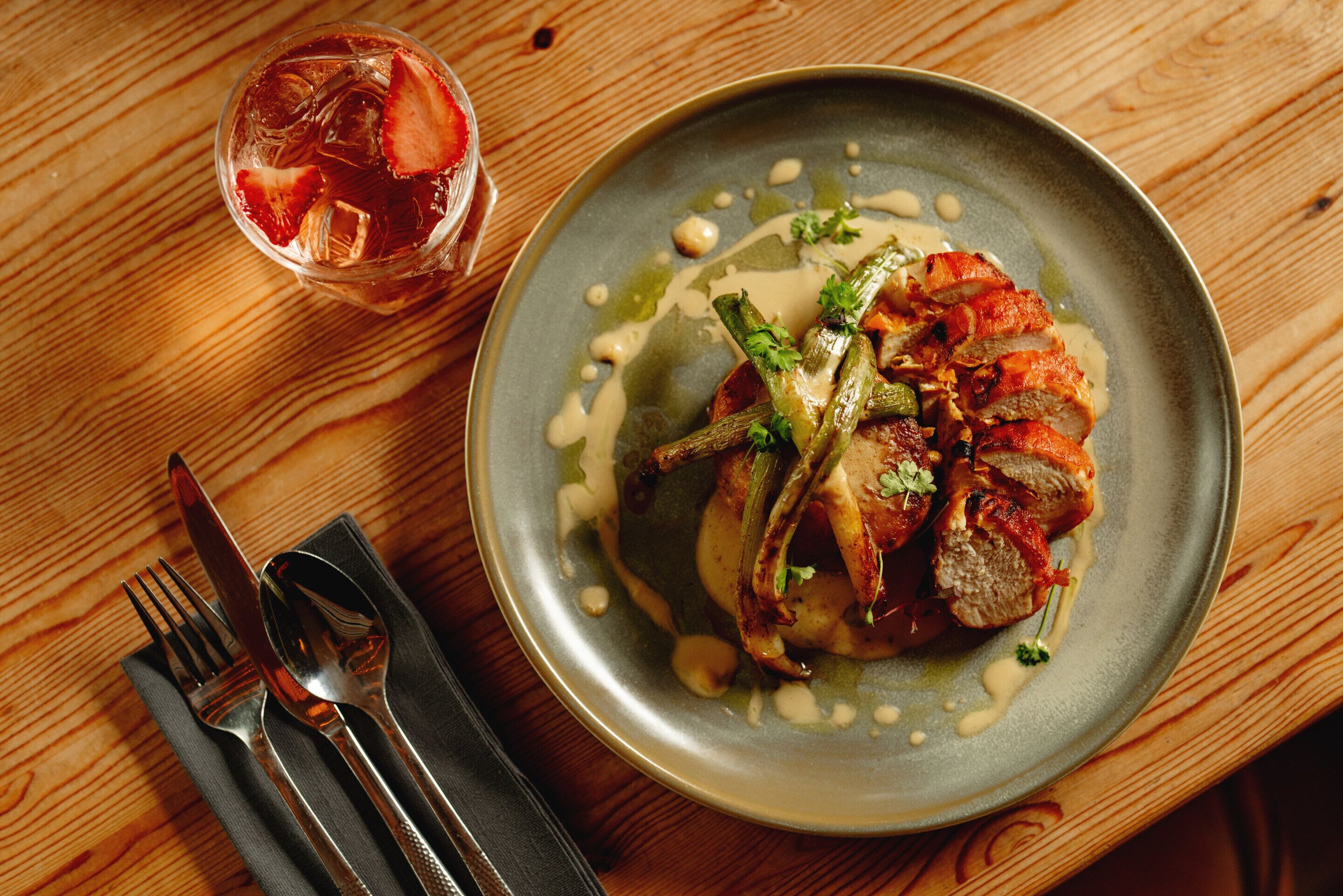 A plate of food with a glass of iced drink on a wooden table.