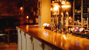A bar counter with multiple beer taps and a selection of beer bottles. - Wheatacre White Lion (Beccles)