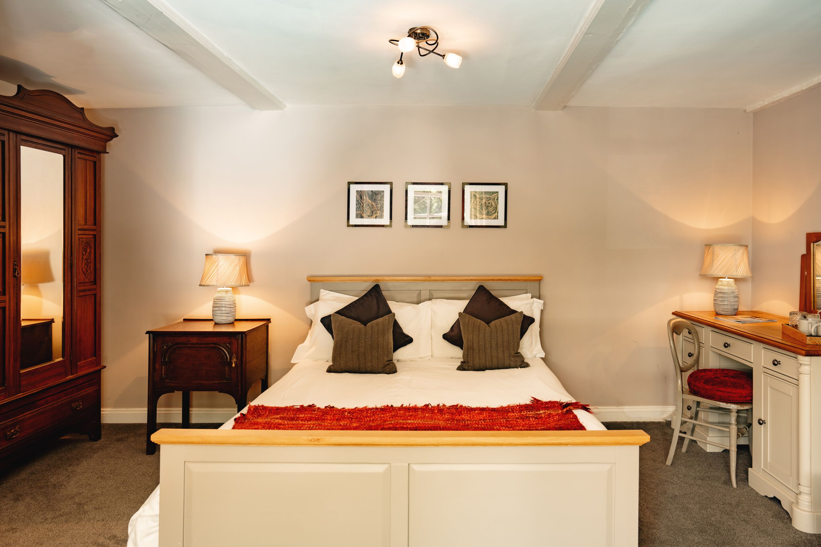 Un dormitorio con cama, mesitas de noche, cómoda y espejo.