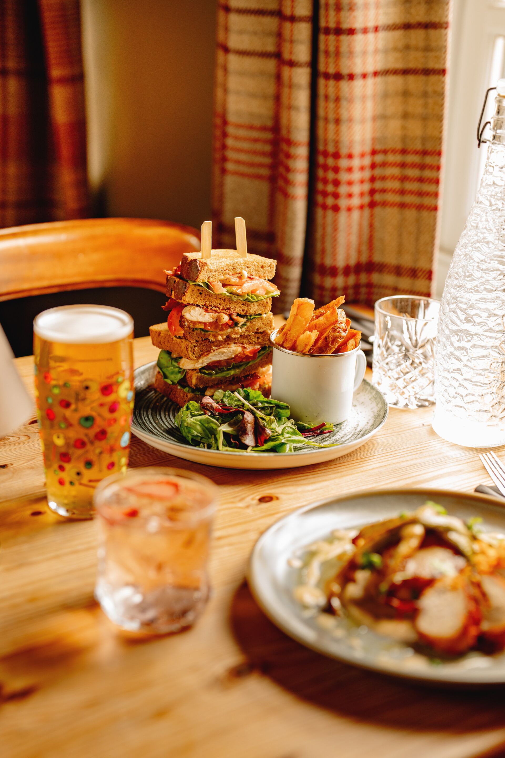 Une table avec un sandwich, une chope de bière, un verre d’eau et une carafe.