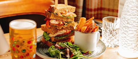 Une table avec un sandwich, une chope de bière, un verre d’eau et une carafe.