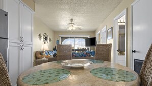 A kitchen with a round table, wicker chairs, and a ceiling fan. - Las Palmas 224 2 Bedroom Condo by RedAwning (Gulf Shores)