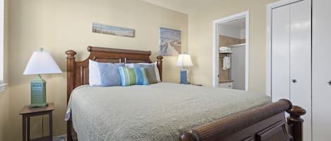A bedroom with a bed, two bedside tables with lamps, a ceiling fan, and a wardrobe.