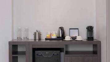 A modern kitchen with a built-in dishwasher, a coffee maker, and a kettle on the countertop.