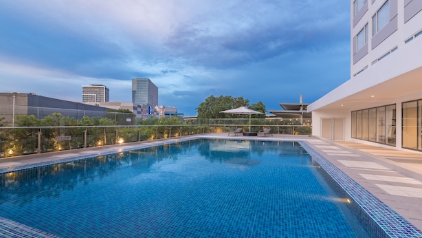 A rooftop pool with a clear view of the city skyline, surrounded by modern buildings and a fence.