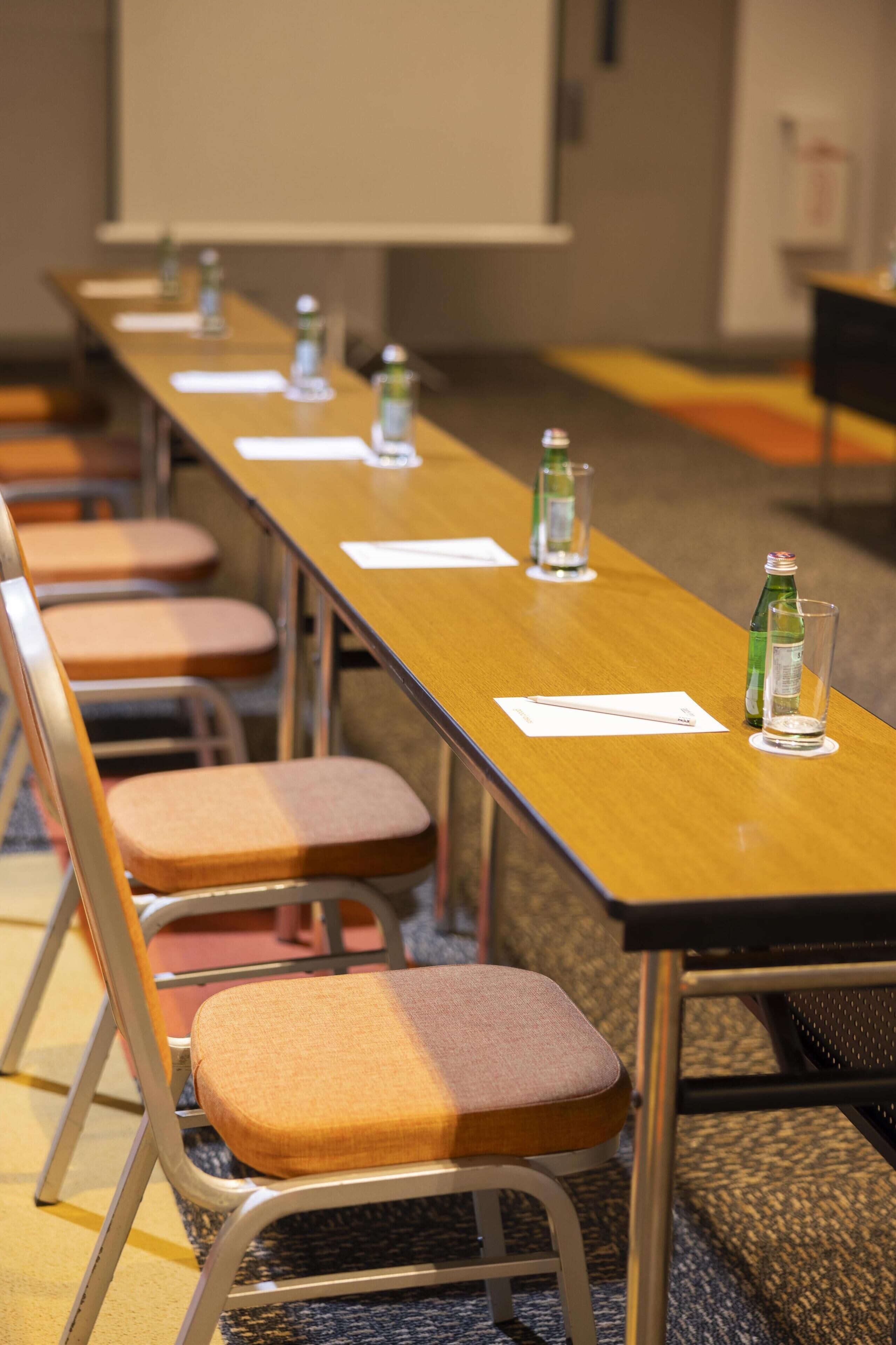 A conference room with a long table, chairs, water bottles, and name cards.