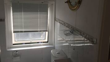 A bathroom with a toilet, sink, and window with blinds.