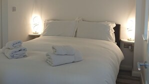 A neatly made bed with white linens and two bedside lamps.